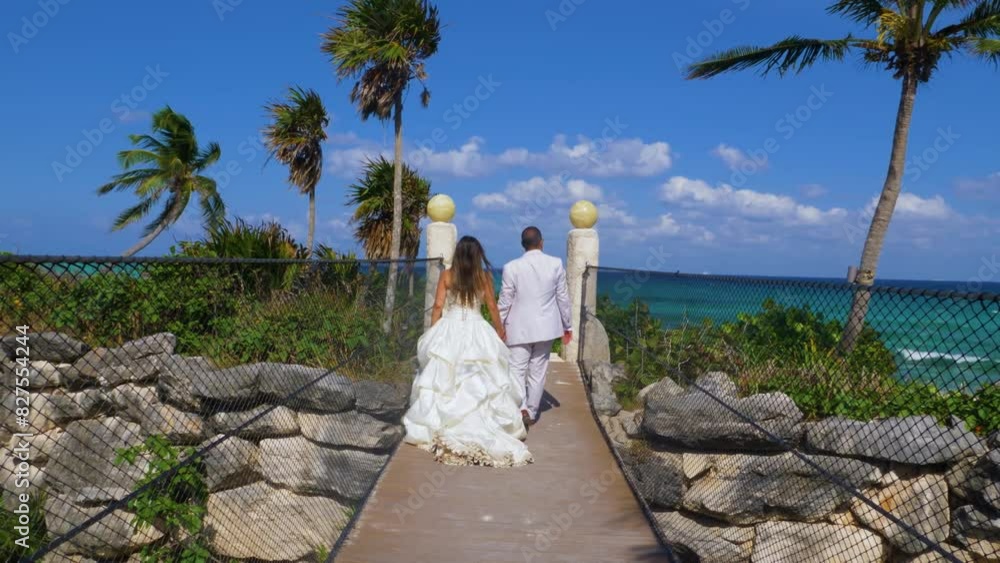 unrecognizable newlyweds walking hand in hand on wooden bridge towards the ocean, trash the dress 60fps unrecognizable newlyweds walking hand in hand on wooden bridge towards the ocean, trash the dress 60fps