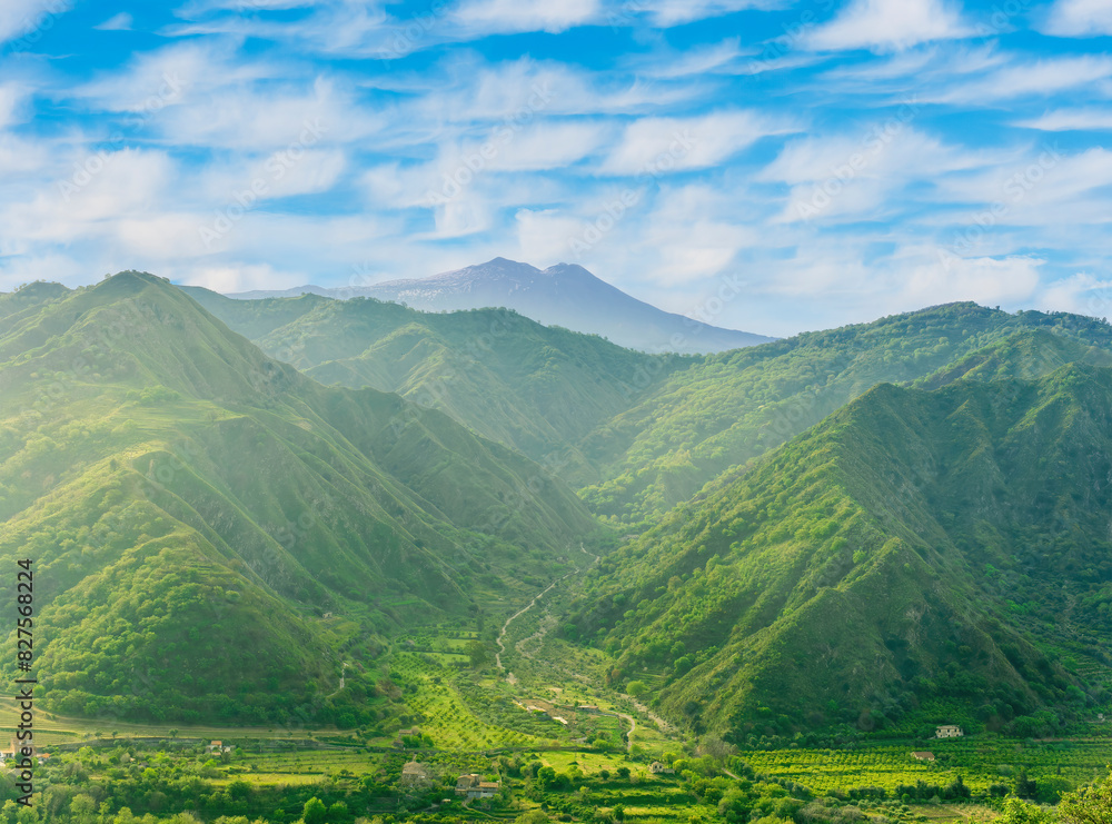 Obraz premium amazing view at a green landscape between two mountains with a high peak with snow and blue cloudy sky on background