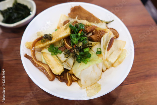 close up of Taiwanese Taiwanese braised dish with pig ear, pork, pig stomach, spring onion and cabbage on a white plate