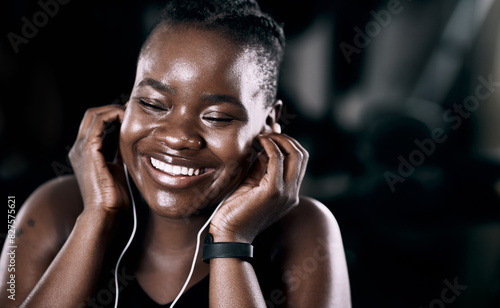 Radio, workout and black woman in gym for cardio, exercise and fitness training with earphones for wellness audio. Podcast, bodybuilder and african lady for health or smile, happy or excited by music