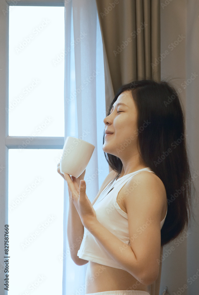 Young asian cute woman standing alone and holding coffee cup at near window and look at outside view and thinking to someone love or something. Coffee time. Young asian cute woman standing alone and holding coffee cup at near window and look at outside view and thinking to someone love or something. Coffee time.