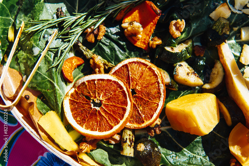 A green salad filled with fresh fruit, nuts, and two dried orange slices in the sun photo