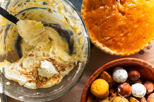half-eaten bannana cream pudding in a large glass serving bowl next to a sweet potato pie and donuts arranged on a table, seen from above photo