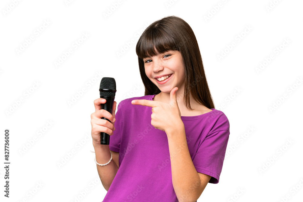 Little singer girl picking up a microphone over isolated background and pointing it Little singer girl picking up a microphone over isolated background and pointing it