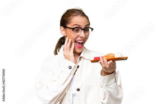 Young caucasian woman holding sashimi over isolated background with surprise and shocked facial expression