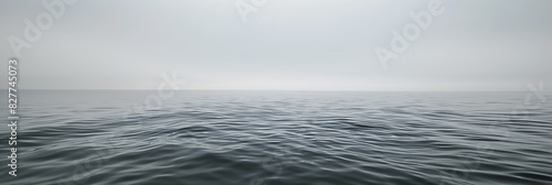 Vast, calm ocean under a gray sky, with gentle waves creating a serene and tranquil seascape.