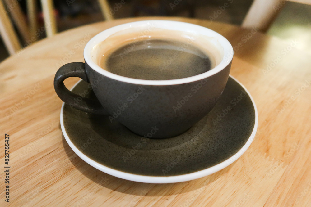 Fototapeta premium close up of black mug cup with hot black americano coffee on a wooden table.