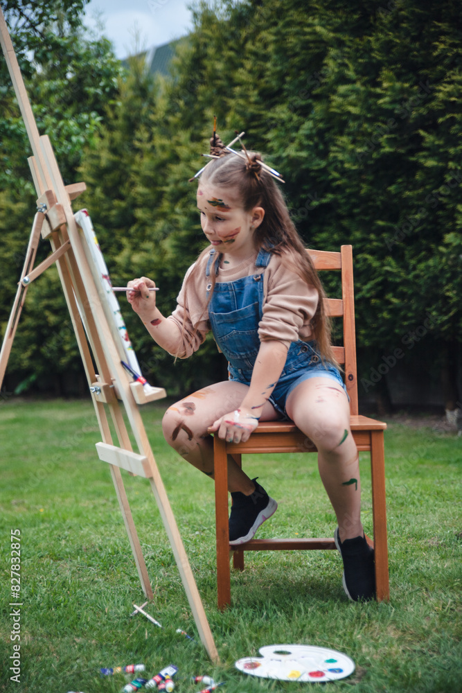 Street artist with easel girl 8 years old European appearance jumpsuit with paints drawing a picture Street artist with easel girl 8 years old European appearance jumpsuit with paints drawing a picture