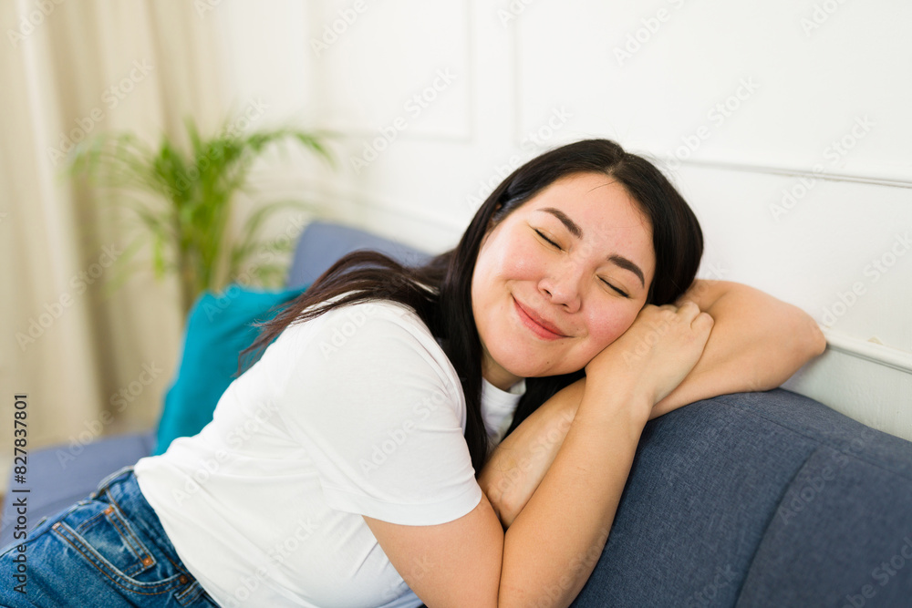 Portrait of a woman comfortably reclining on couch with eyes closed, expressing peaceful contentment in a bright, cozy living room setting Portrait of a woman comfortably reclining on couch with eyes closed, expressing peaceful contentment in a bright, cozy living room setting
