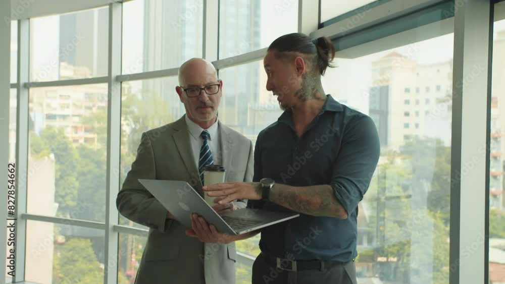 Medium shot of multiethnic male manager showing mature Caucasian CEO plan of project on wireless laptop at modern office Medium shot of multiethnic male manager showing mature Caucasian CEO plan of project on wireless laptop at modern office