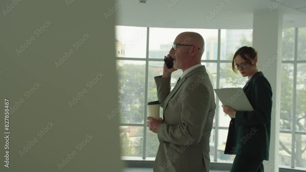 Tracking shot of female secretary following mature businessman talking on mobile phone at contemporary coworking space Tracking shot of female secretary following mature businessman talking on mobile phone at contemporary coworking space