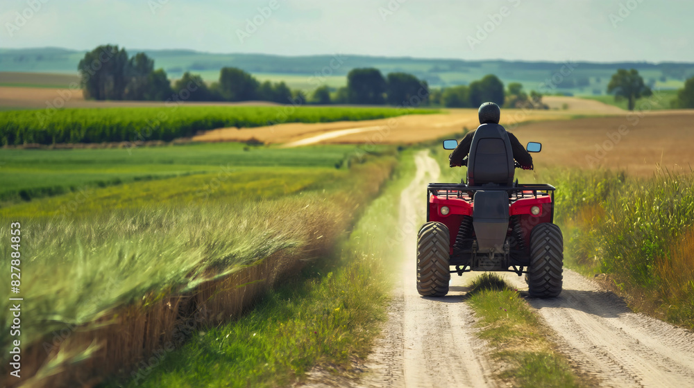 Rear back view of man wearing a helmet, driving ATV motocross quad bike on rural countryside field village road outdoors in the summer. Copy space, off-road terrain trail transport, mountain lifestyle Rear back view of man wearing a helmet, driving ATV motocross quad bike on rural countryside field village road outdoors in the summer. Copy space, off-road terrain trail transport, mountain lifestyle