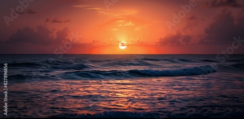 The sun is setting over the ocean  casting a warm glow on the water