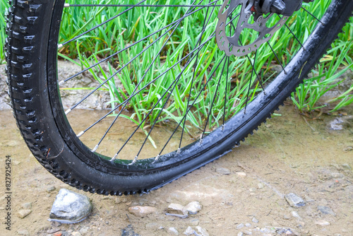 The sturdy tread of a trekking bike tire is showcased in a puddle off the beaten path on a rugged field trail. It hints at an adventure beyond the ordinary routes.