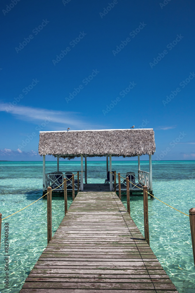 Pier leading into the sea with clear blue sky and turquoise water as beach vacation lifestyle scenery Pier leading into the sea with clear blue sky and turquoise water as beach vacation lifestyle scenery