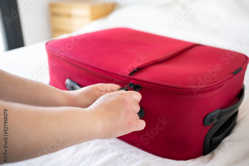 Close up hand of a young woman closing her red suitcase.