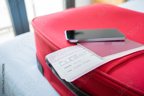 Passport,air ticket and smart phone on a red suitcase on a bed at hotel