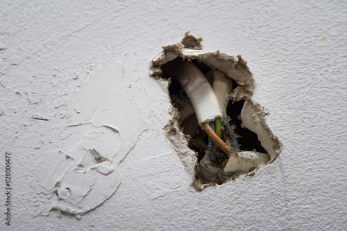 Damaged Wall With Exposed Electrical Wires Inside a Residential Home During Daytime