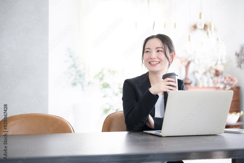 オフィスでコーヒーを持ちパソコンを使う見上げる女性 転職や採用などの明るいイメージにも コピースペースあり オフィスでコーヒーを持ちパソコンを使う見上げる女性 転職や採用などの明るいイメージにも コピースペースあり