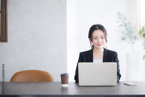 逆光の綺麗なオフィスでパソコンを使う女性の上半身アップの正面のビジネスシーン　コピースペースあり