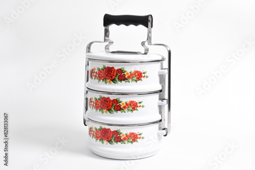 Vintage Tiffin or metal food container with floral motif isolated on white background photo