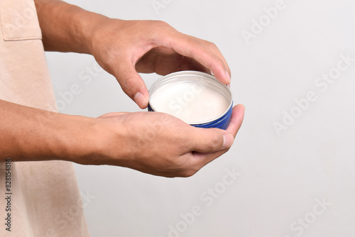 Man's hand holding pomade or waxe for hair styling isolated on white background