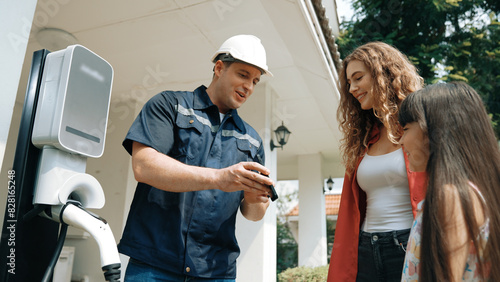 Technician install home EV charging station, providing service support for EV app on customer smartphone for monitoring charging status and set charging schedules at home. Synchronos photo