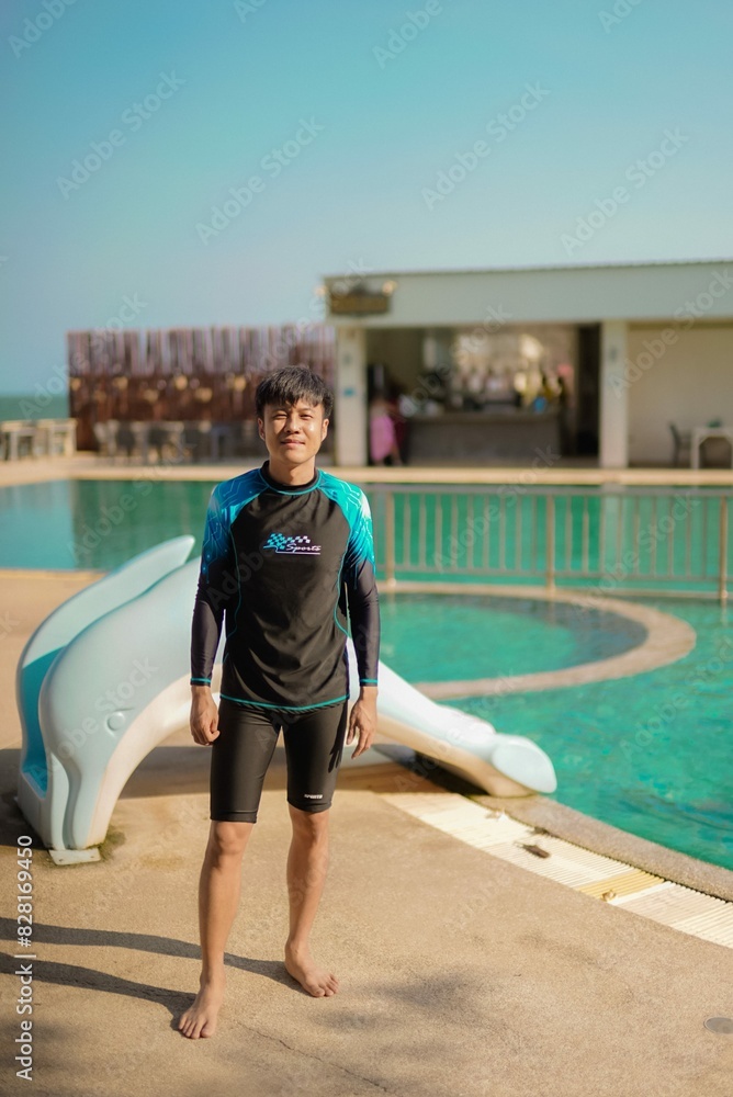 Obraz premium asian man standing in swimming pool with dolphin slider