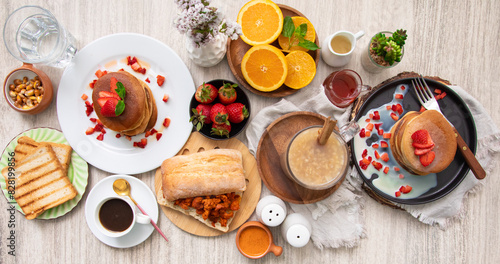 Breakfast table full of food brunch pancakes, bread and fruit