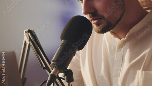 Bearded guy blogger speaking into microphone in slow motion. Close up caucasian man recording his life stories podcast. Male podcaster host working with mic. Content creator broadcasting