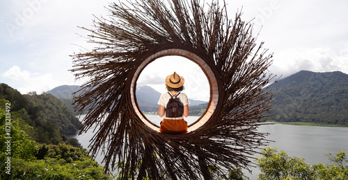 Female traveler contemplating nature sitting in straw nest looking at lake view in Munduk, Bali. Banner image. photo