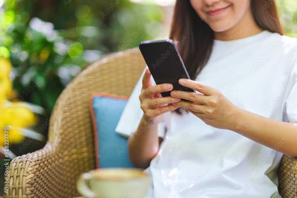 Closeup image of a young woman holding and using mobile phone in the outdoors cafe Closeup image of a young woman holding and using mobile phone in the outdoors cafe