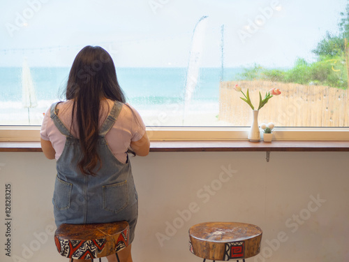 View sea seen through cafe with rear view of woman relaxing on bar.