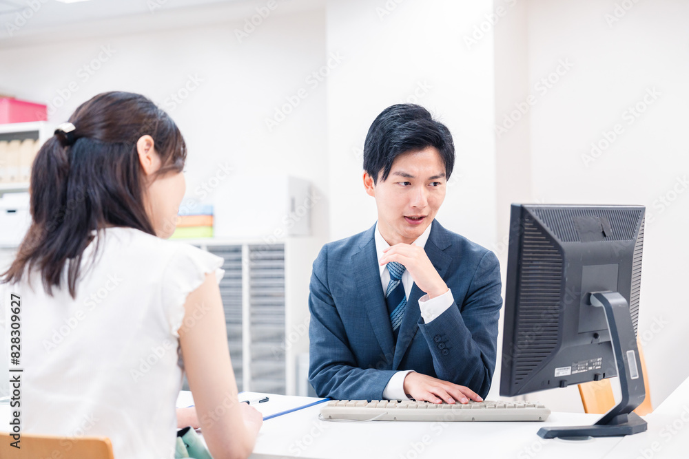 不動産会社のカウンターで相談をする若い女性 不動産会社のカウンターで相談をする若い女性