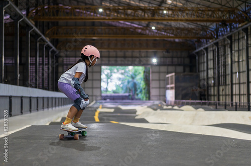 surfskate by asian child skater or kid girl start riding surf skate at indoor pump track and fun playing skateboard in skate park by extreme sports surfing to wears helmet wrist knee guard body safety