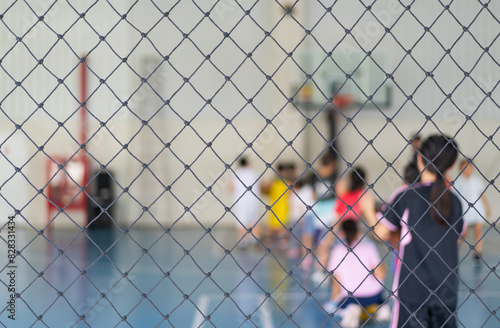 blur basketball court by rope mesh net fence focus with many asian children or kid learning training to playing basketball with child coach and basketball hoop for healthy sport exercise background