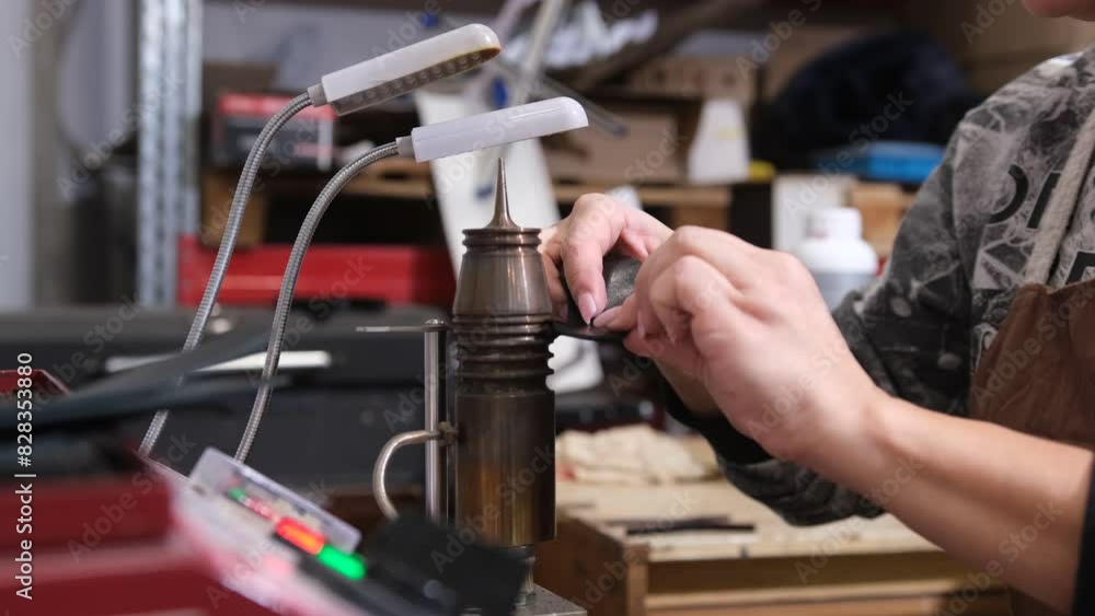 A leatherworker carefully uses a specialized tool to work on a leather piece, her hands focused and precise. A leatherworker carefully uses a specialized tool to work on a leather piece, her hands focused and precise.