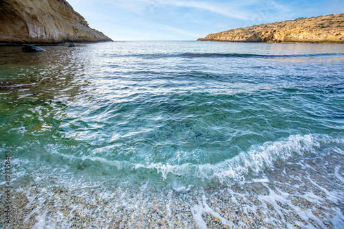 Small waves breaking in the Cala Blanca of crystal clear emerald green waters in the Puntas de Calnegre regional park in the Region of Murcia, Spain photo