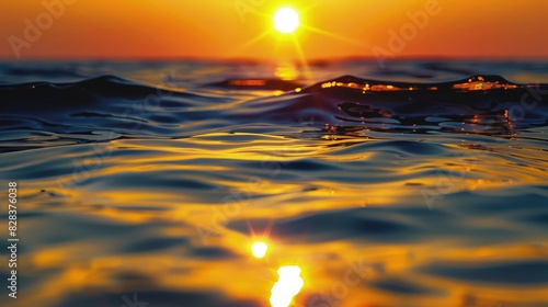 A stunning beach scene with the sun setting on the horizon, casting golden hues across the sky and reflecting on the calm waves, with footprints leading towards the water.
