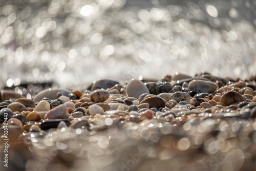 Pebbles on the shore of a Mediterranean beach with bokeh effect from the glow of the waves