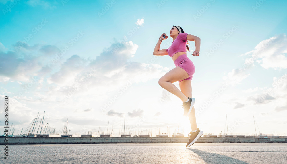 Fit woman exercising outside - Athletic young female doing fitness workout on city street - Sport life style concept with active girl jogging outdoors