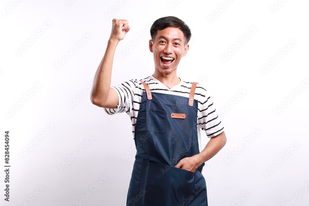 Cheerful asian seller making fist pump, rejoicing and triumphing, standing in blue apron against white background. Cheerful asian seller making fist pump, rejoicing and triumphing, standing in blue apron against white background.