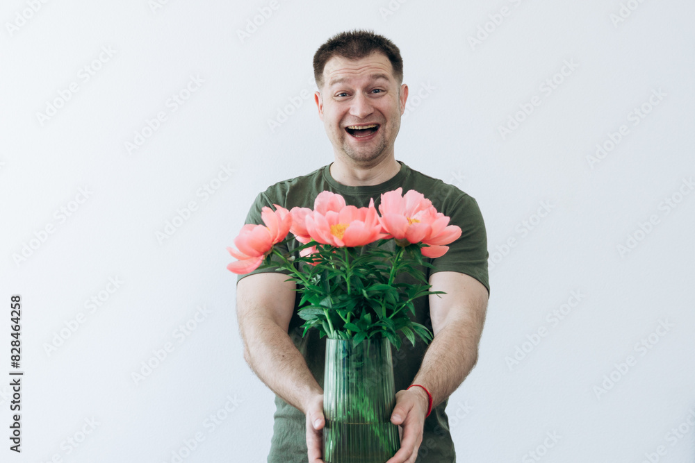 A guy holds a vase with peonies in his hands A guy holds a vase with peonies in his hands