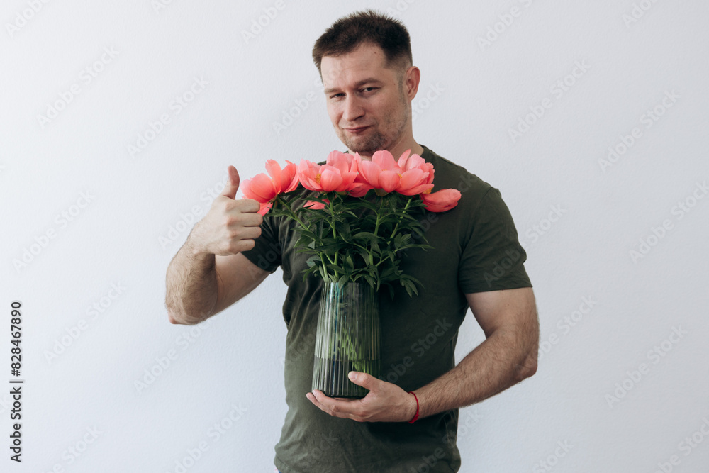 A guy holds a vase with peonies in his hands A guy holds a vase with peonies in his hands