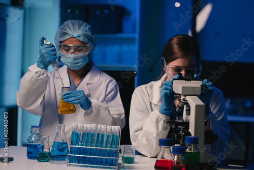 Team of biochemical research scientists working with a microscope for vaccine development.