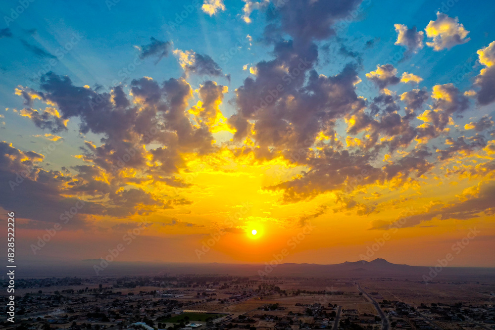 the sun sets over a town and hills as seen from above