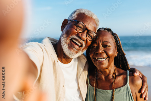 Joyful senior African American couple taking a selfie by the sea photo