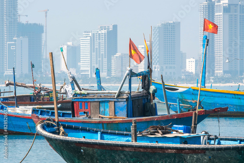 View of traditional Vietnamese fishing boats with flags on the background of the city on sunny day. Da Nang, Vietnam.