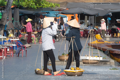 Vietnamese street vendors sell fruits in Hoi An ancient town on sunny day. Vietnam.