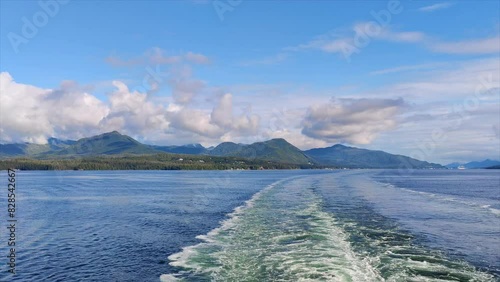 The water ripples from a sailing boat with a mountain in the background in Ketchikan, Alaska photo